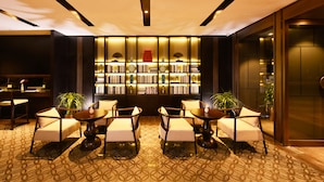 Eine moderne Hotelhalle mit einer zentralen Sitzgruppe, einem Bücherregal und einer Rezeption.