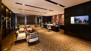 Eine moderne Lobby mit Empfangsschalter, Sitzgelegenheiten und einem großen Bildschirm, der eine Stadtansicht zeigt.
