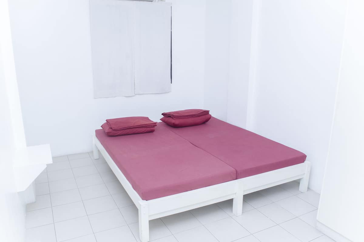 A white room with a single bed, a white wall, and a white floor.