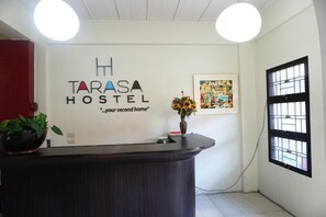 A reception desk at Tarasa Hostel with a modern design, a logo, and a quote on the wall. - Tarasa Hostel (Pasay)