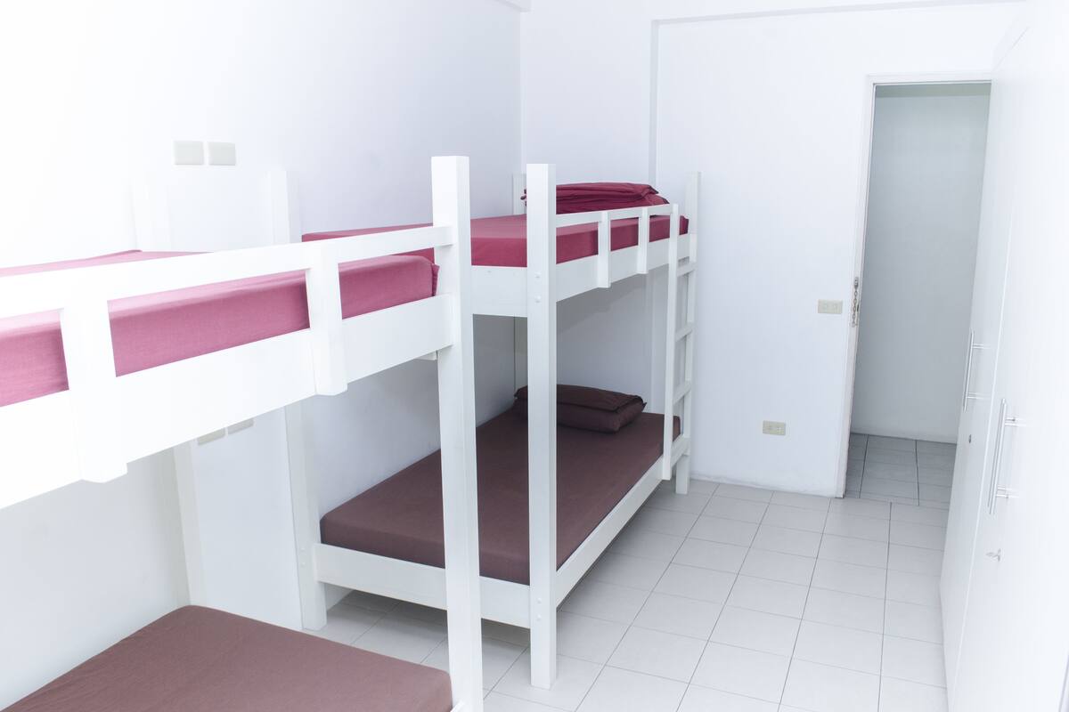A room with bunk beds and a door leading to another area.