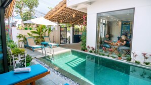 A modern outdoor pool area with lounge chairs, a wooden deck, and potted plants. - An Bang Beach Dolphin Homestay Hoi An (Da Nang)