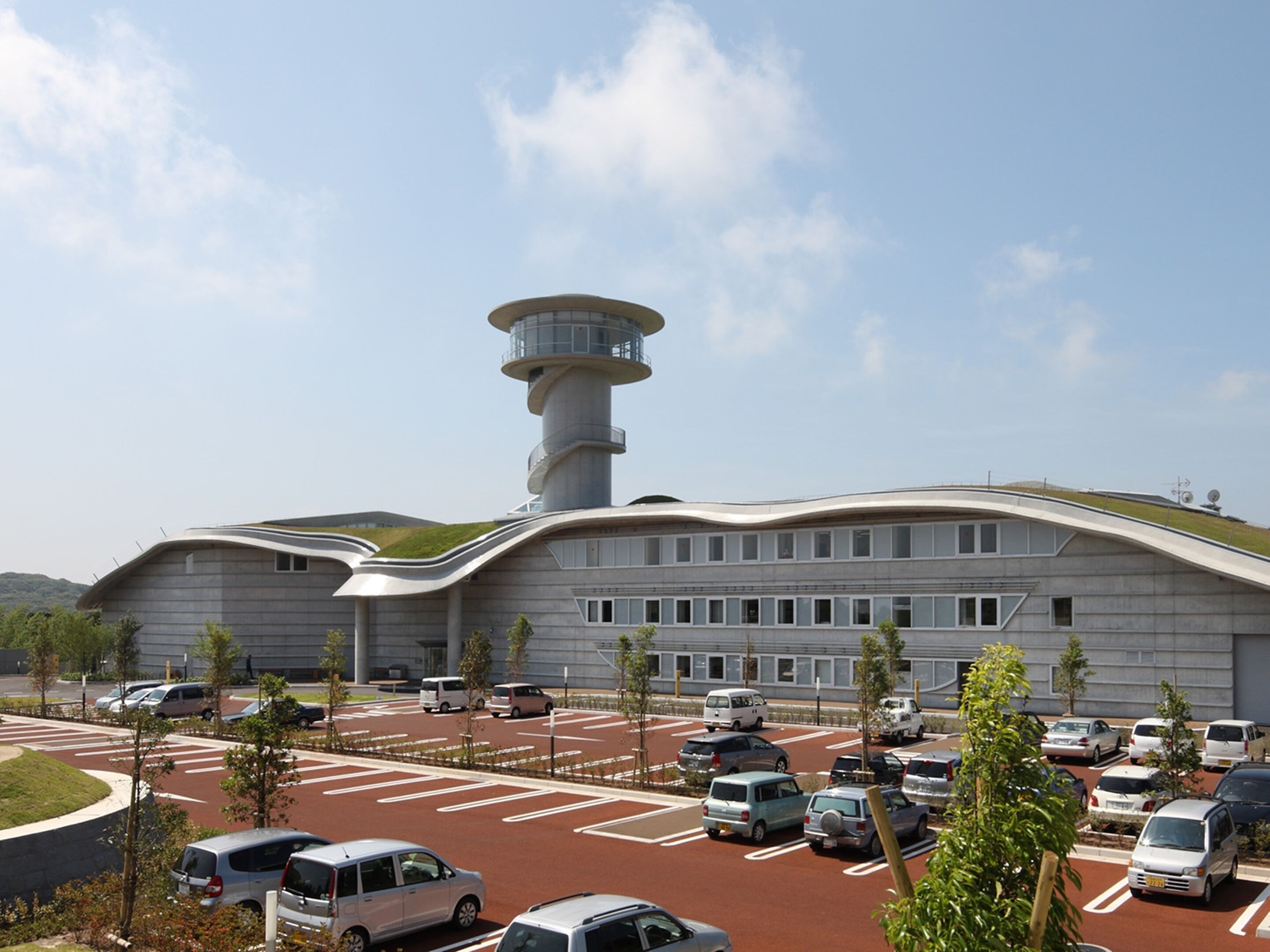 A modern building with a unique curved roof and a central tower.