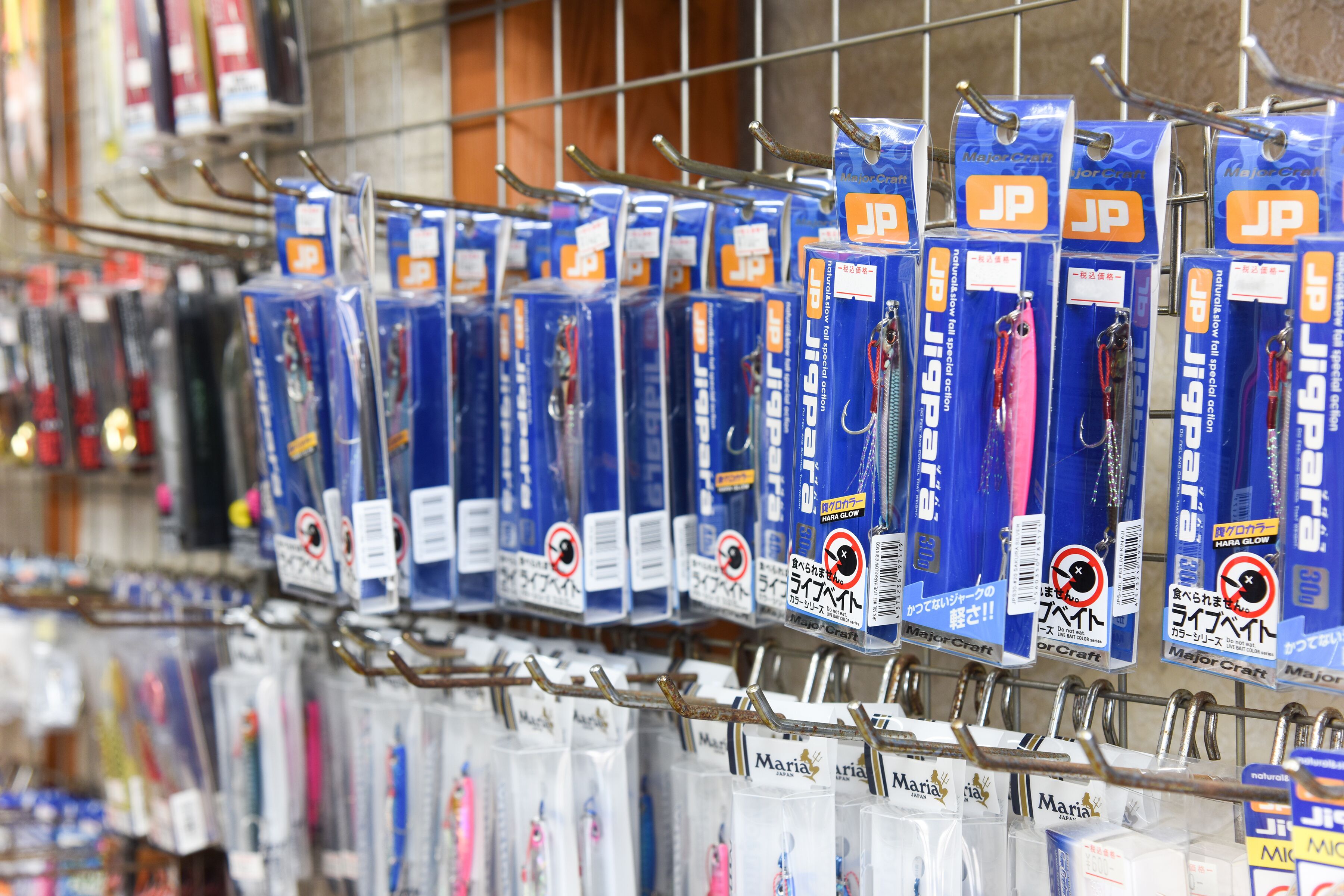 A display of fishing tackle boxes with JP branding, arranged on a metal rack in a store.