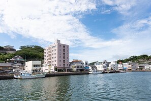 A waterfront with a docked boat, buildings along the shore, and a clear sky. - Iki Marina Hotel (Iki)