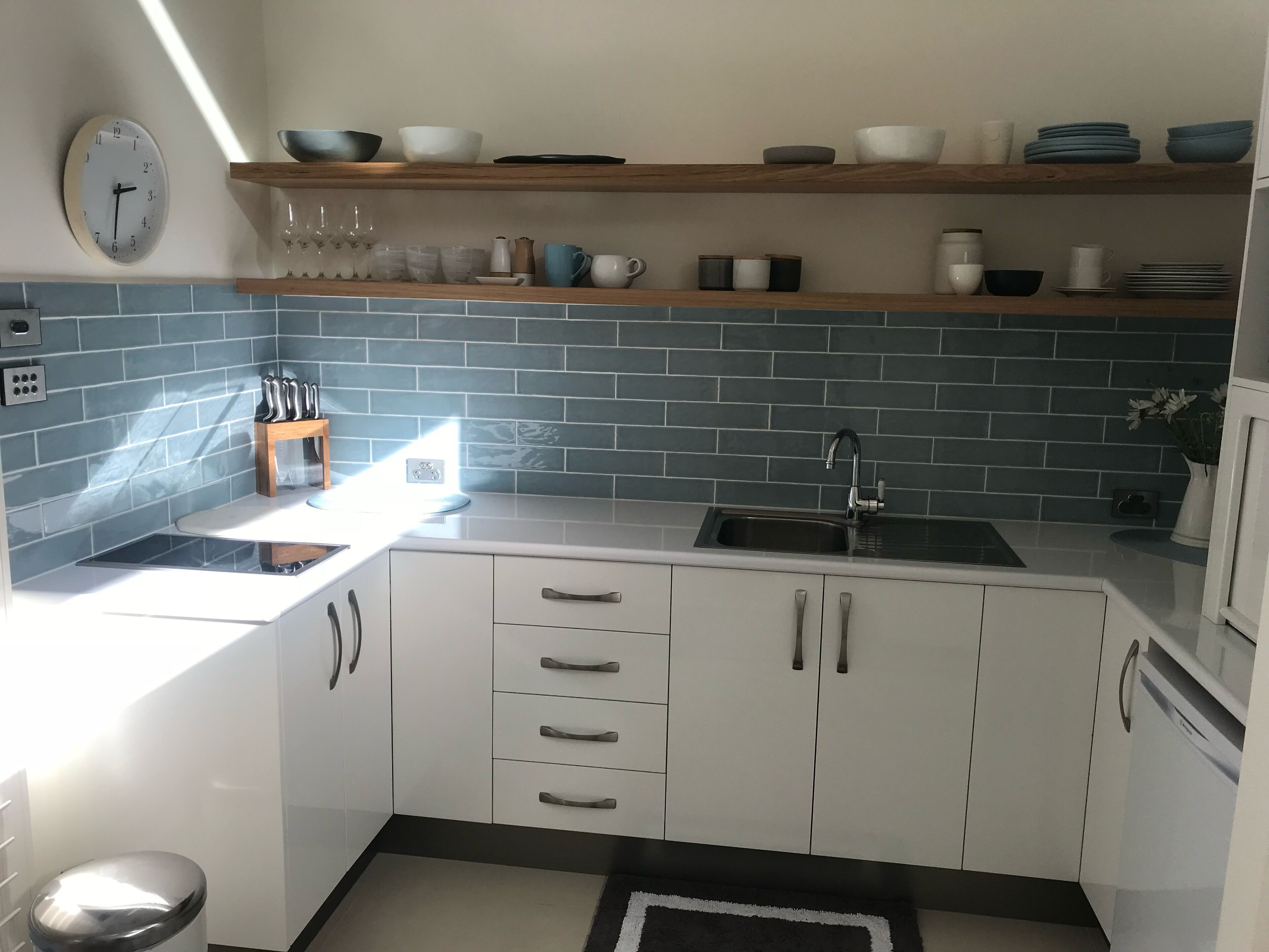Eine moderne Küche mit weißen Schränken, einer schwarzen Arbeitsplatte und einer blauen Spritzschutzwand.