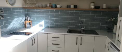 Eine moderne Küche mit weißen Schränken, einer schwarzen Arbeitsplatte und einer blauen Spritzschutzwand.