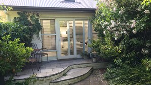 Ein überdachter Patio-Bereich mit Sitzgelegenheit und Topfpflanzen.