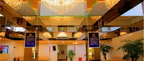 Un'ampia hall con soffitto alto, un lampadario centrale e una reception.