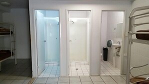 Une chambre de dortoir avec des lits superposés, une douche et un lavabo.