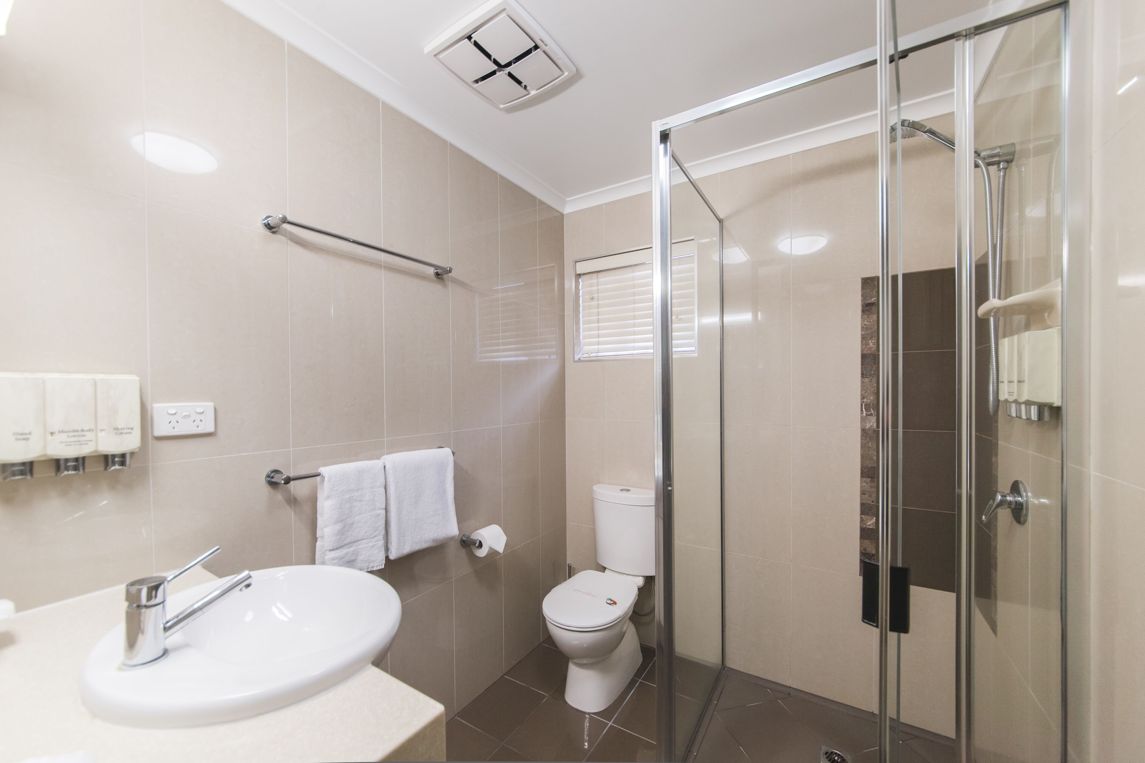A modern bathroom with a glass-enclosed shower, a white sink, and a toilet.