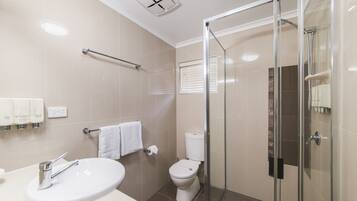 A modern bathroom with a glass-enclosed shower, a white sink, and a toilet.