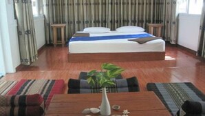 Une chambre d’hôtel avec un lit, une table en bois ornée d’un vase et de quelques pierres, et un canapé.