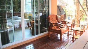 Une terrasse en bois avec une table et des chaises, de grandes portes vitrées et une vue sur l’extérieur.