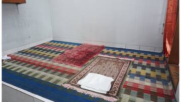 Una habitación con un tapete grande y colorido, otro más pequeño con estampado, y un paño blanco sobre un tapete a juego.