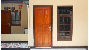 Una puerta de madera con el número 109, una ventana con diseño de cuadrícula y una zona de entrada con baldosas.