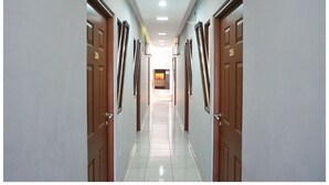 A corridor with doors on both sides, leading to a bright room at the end. - Budi House & Food Station (Cimahi)