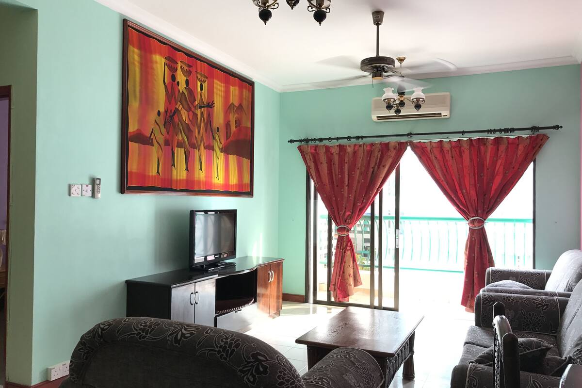Una sala de estar con una televisión, una mesa y dos sofás.