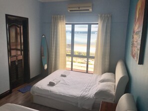 Une chambre d’hôtel avec un lit, une fenêtre avec des rideaux, un climatiseur fixé au mur et une porte avec un miroir.