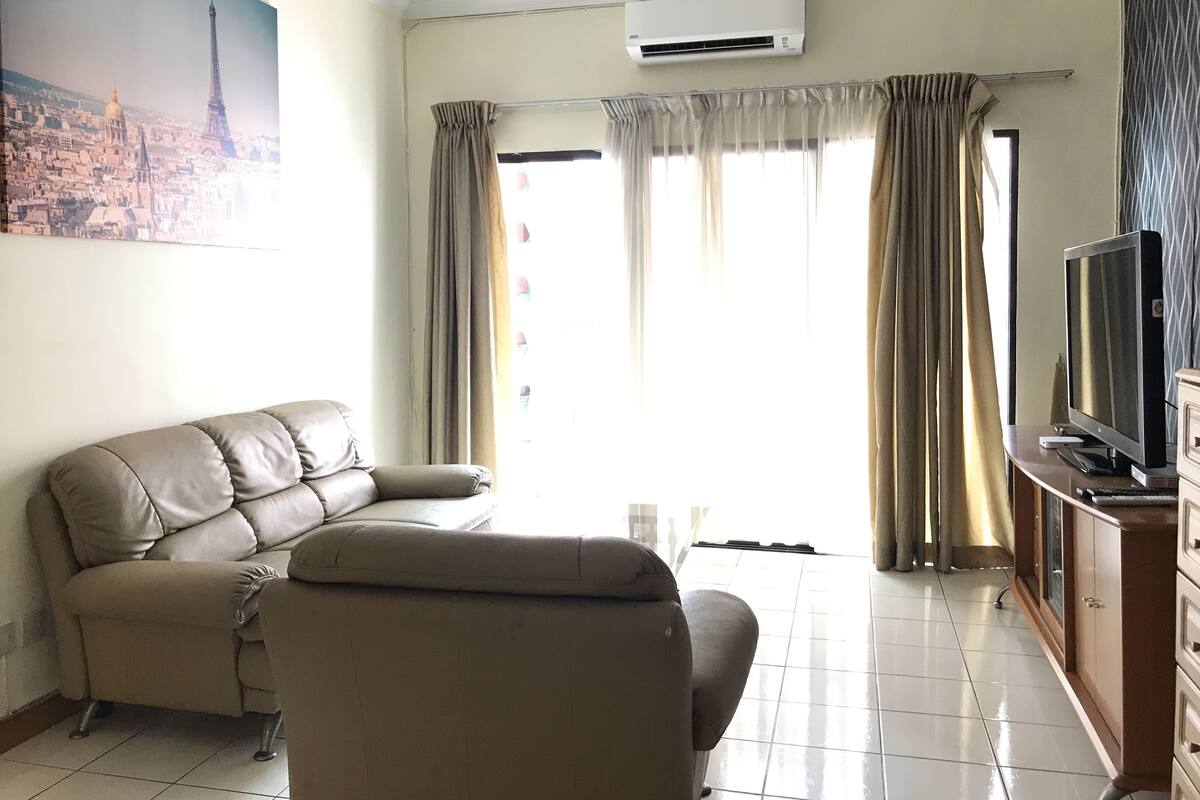 Una sala de estar con un sofá, un televisor y cortinas.