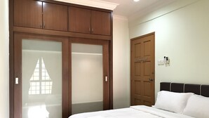 A bedroom with a bed, a wardrobe with frosted glass doors, and a plain wall with a door. - Sunset & Seaview Vacation Condos at Marina Court Resort Condo (Kota Kinabalu)
