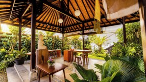 Un patio al aire libre con mobiliario de madera y una estructura de techo de paja.