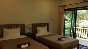 A hotel room with two single beds, a bedside table with a lamp, a ceiling fan, and a view of greenery through a sliding glass door. - Khao Sok Palm Garden Resort (Phanom)