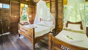 A wooden cabin with two wooden beds, each with a canopy.