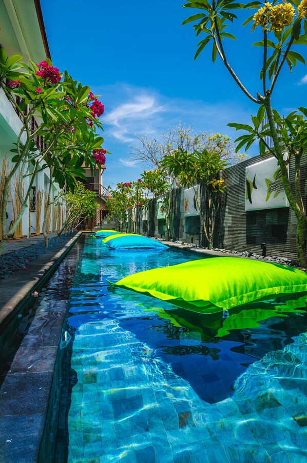 A swimming pool with clear water, surrounded by greenery and modern architecture.
