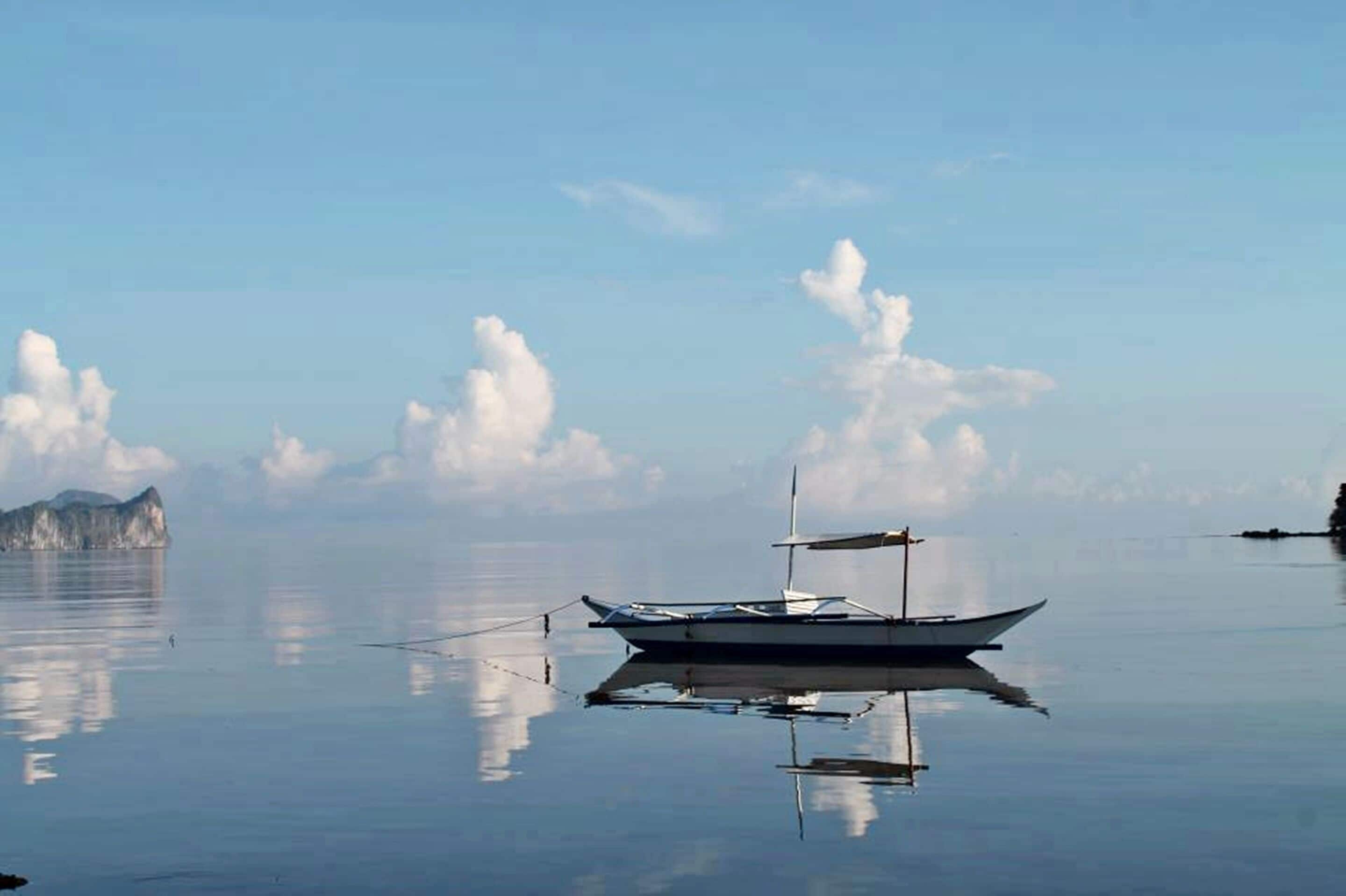 A calm body of water with a boat anchored near the shore.