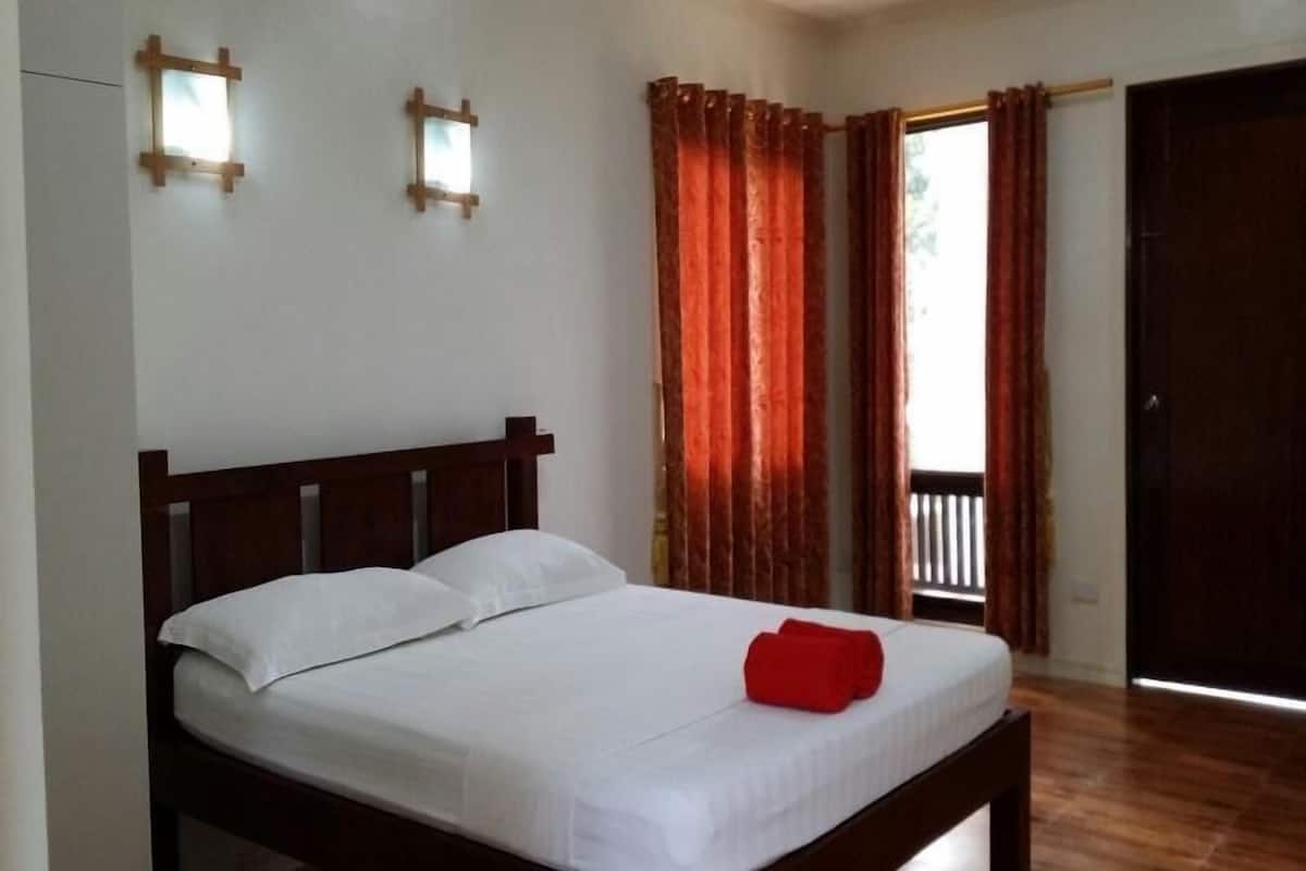 A single bed with a wooden headboard, white bedding, and a red towel.