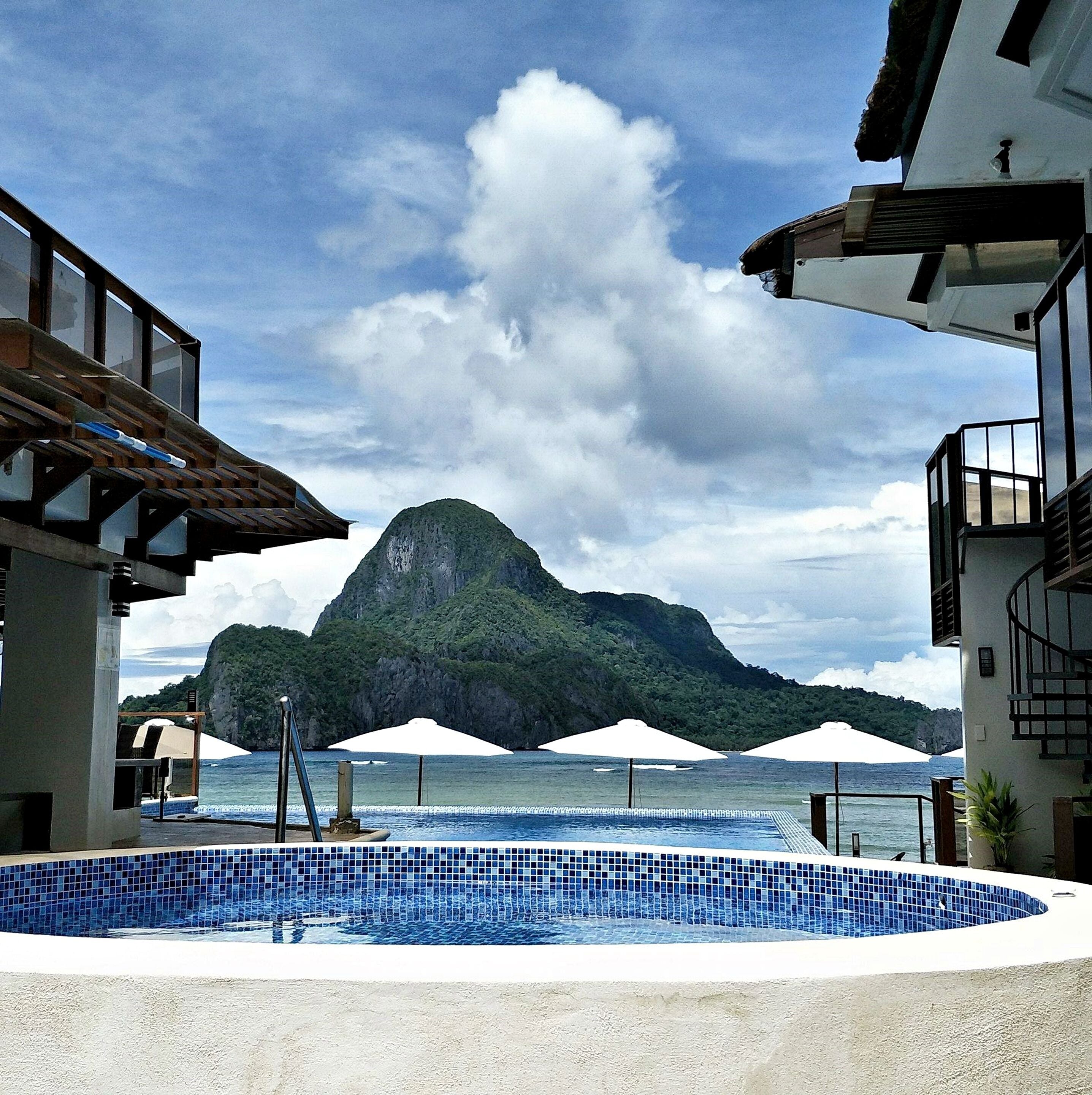 A pool area with a view of a mountain and ocean.