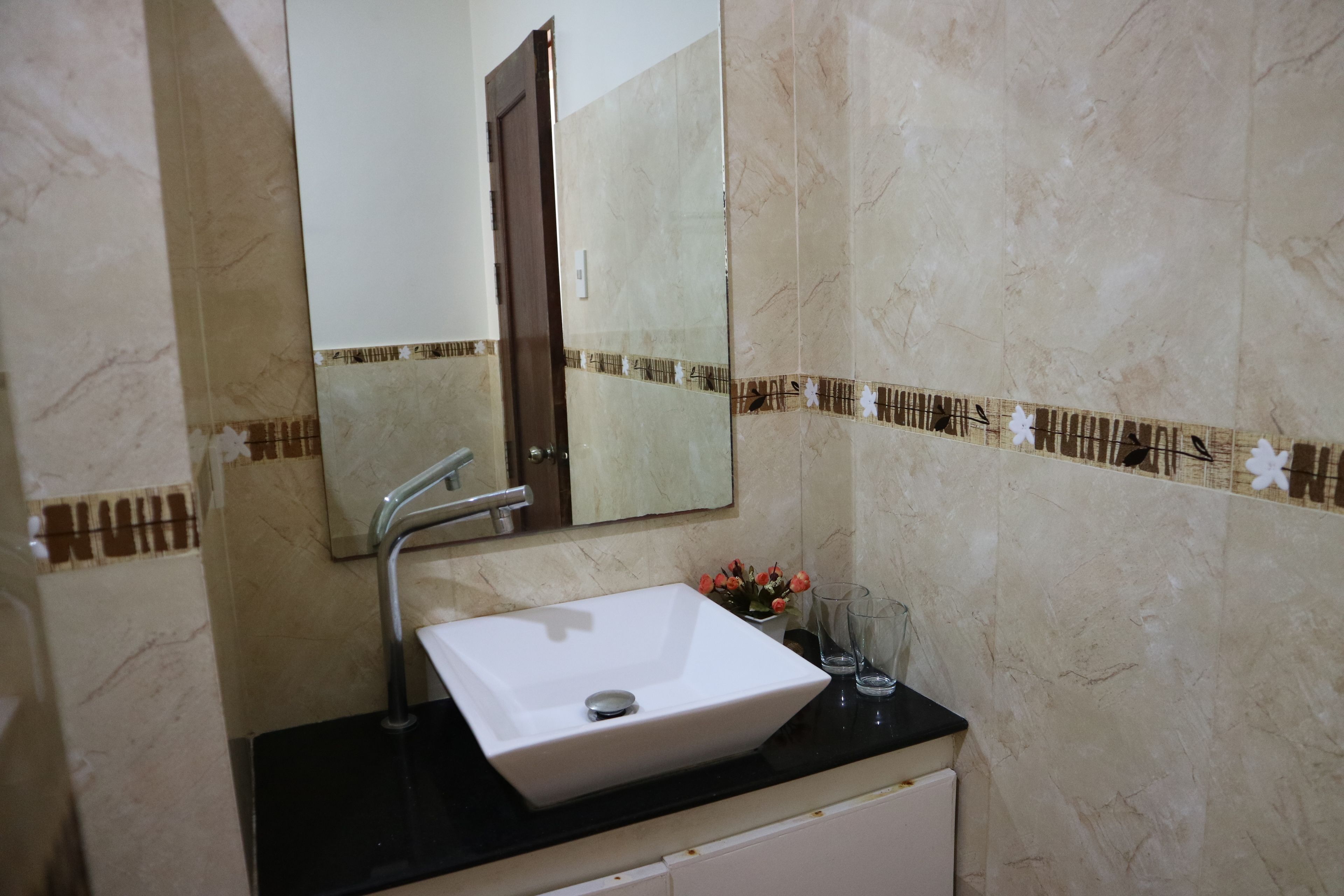 A bathroom with a white sink, a mirror, and a decorative tile border.