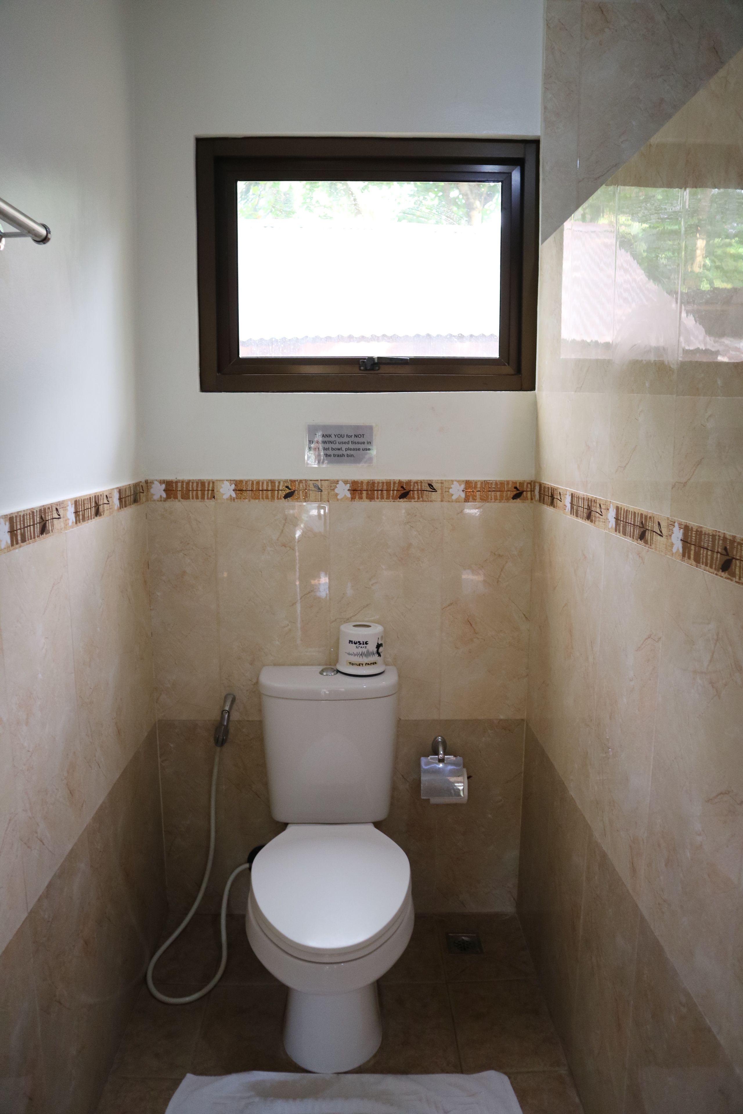 Een kleine badkamer met toilet, raam en douche.