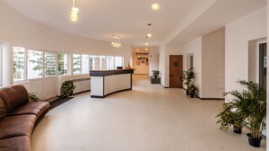 A spacious lobby with a reception desk, a curved sofa, and potted plants. - Fiestaa Resort n Events Venue (Bengaluru)
