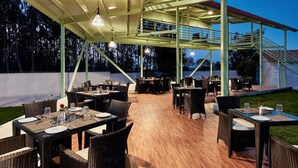 An outdoor dining area with tables and chairs, a covered seating area, and a view of the surrounding landscape. - Fiestaa Resort n Events Venue (Bengaluru)