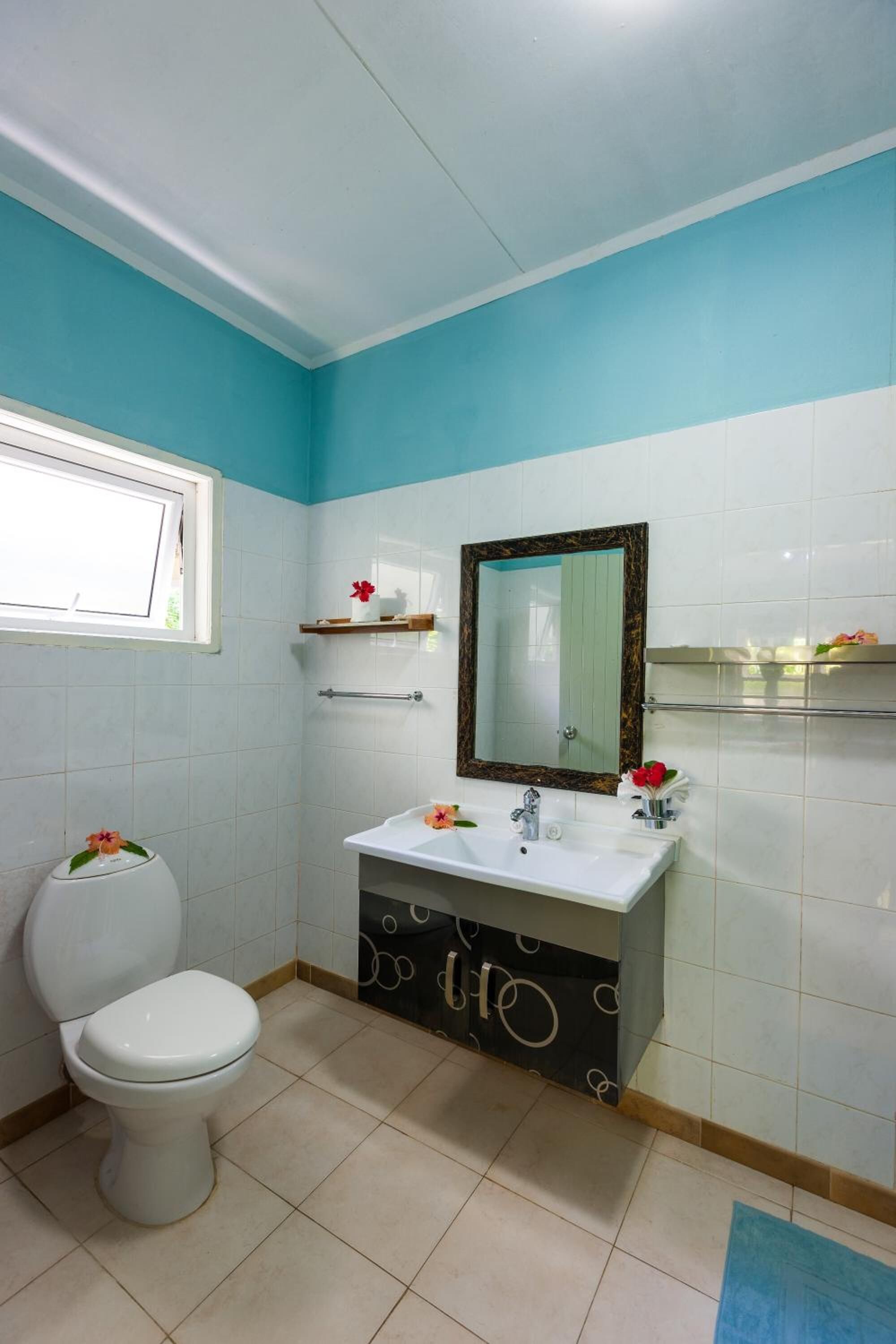 Un baño con inodoro, lavamanos, espejo y ventana.