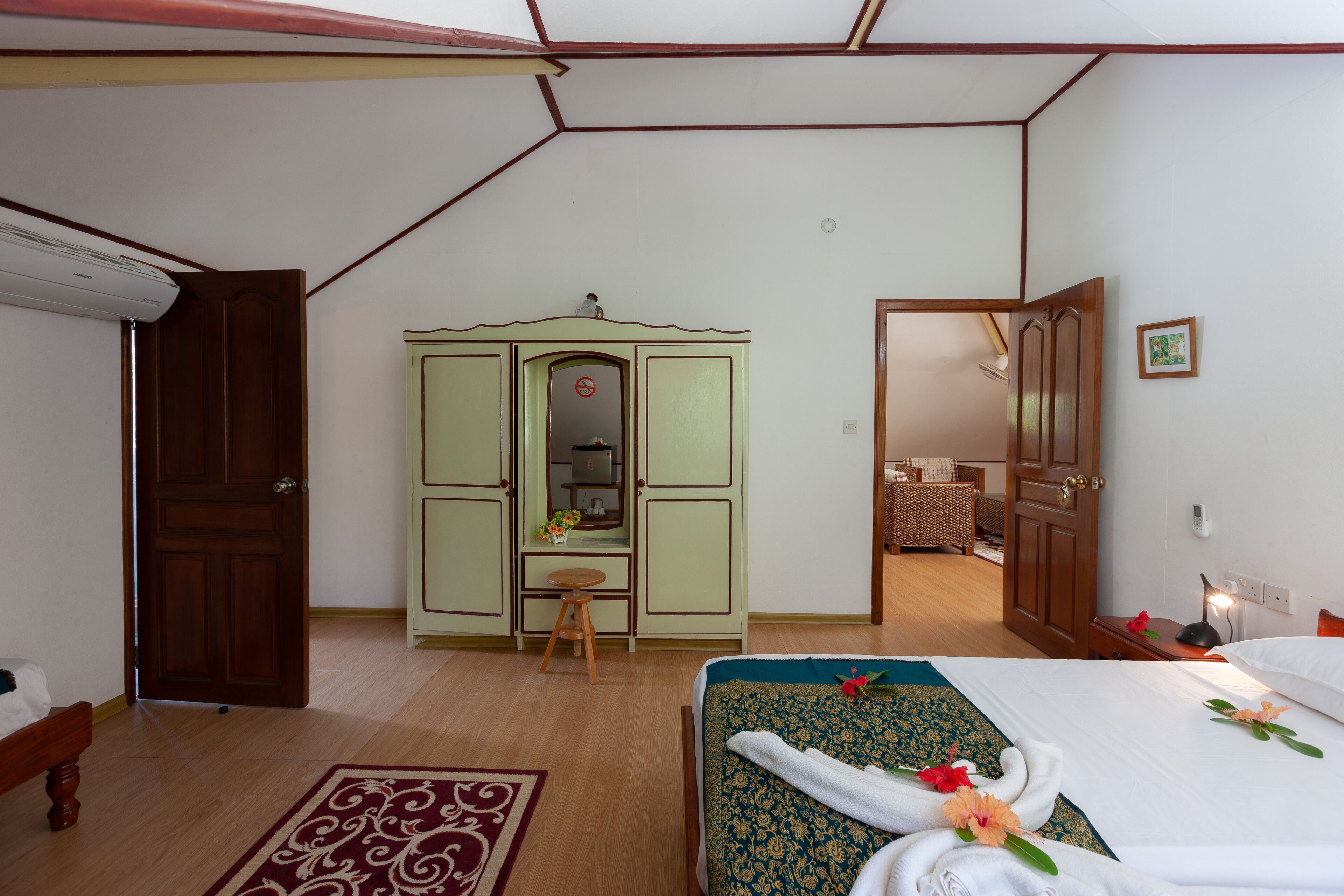 Habitación de hotel con una cama, un armario de madera, un taburete pequeño y un escritorio con espejo.