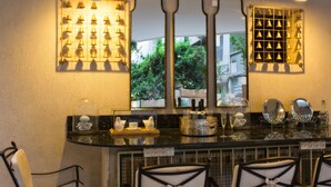 A bar area with a mirror, bottles, glasses, and chairs. - A23 Boutique Hotel (Tel Aviv)