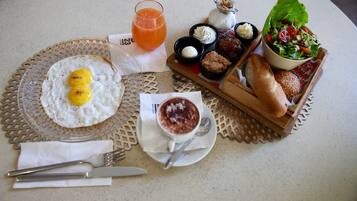 Un desayuno con huevos, tostadas, un vaso de zumo de naranja, ensalada en un bol y una taza de café.