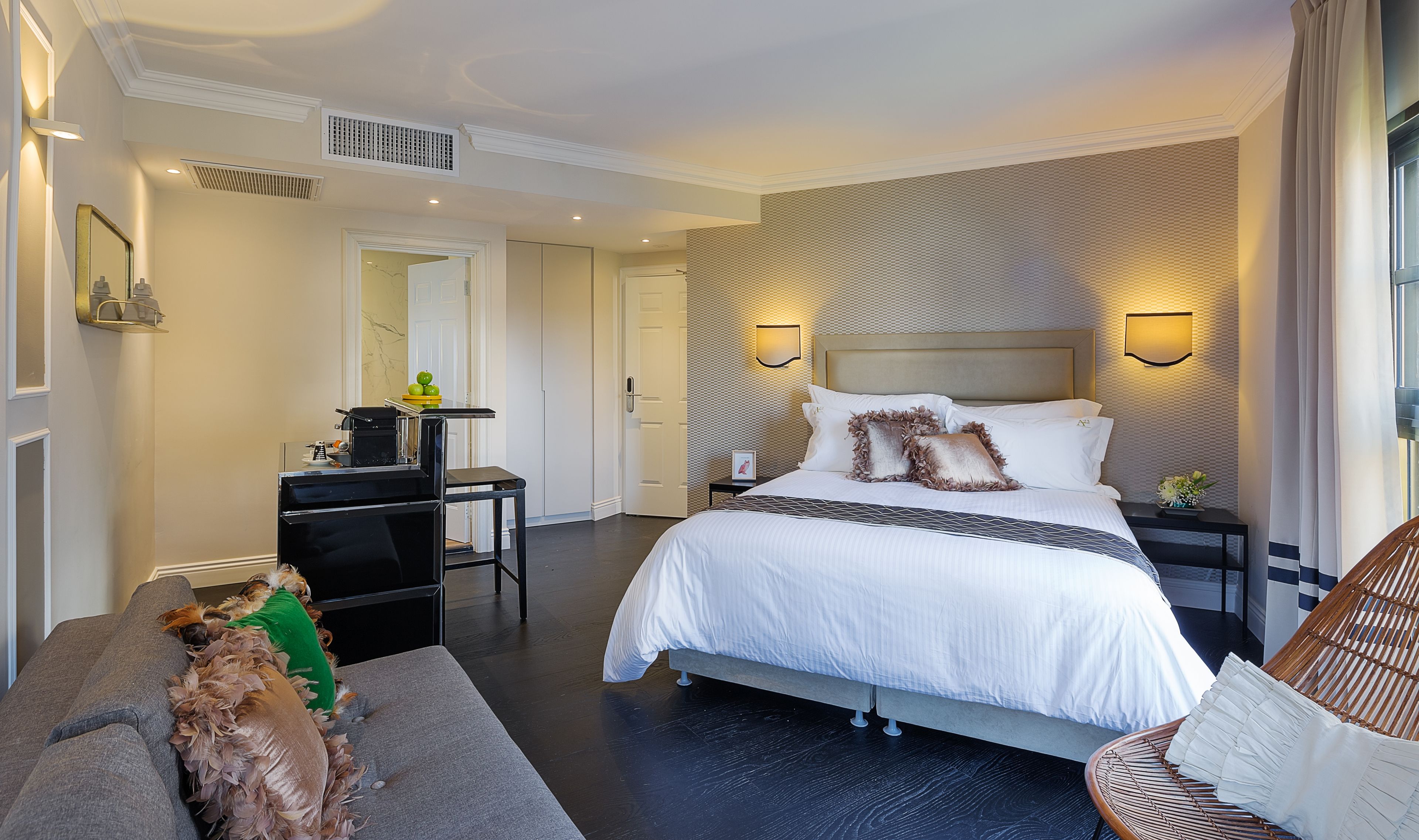 Ein modernes Hotelzimmer mit einem großen Bett, einem kleinen Schreibtisch, einem Sessel und einem Schlafsofa.
