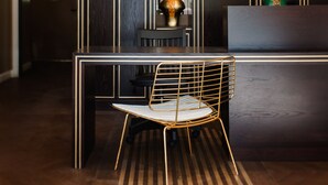 A modern reception area with a dark wood panel wall, a round mirror, a gold-framed chair, and pendant lighting. - A23 Boutique Hotel (Tel Aviv)