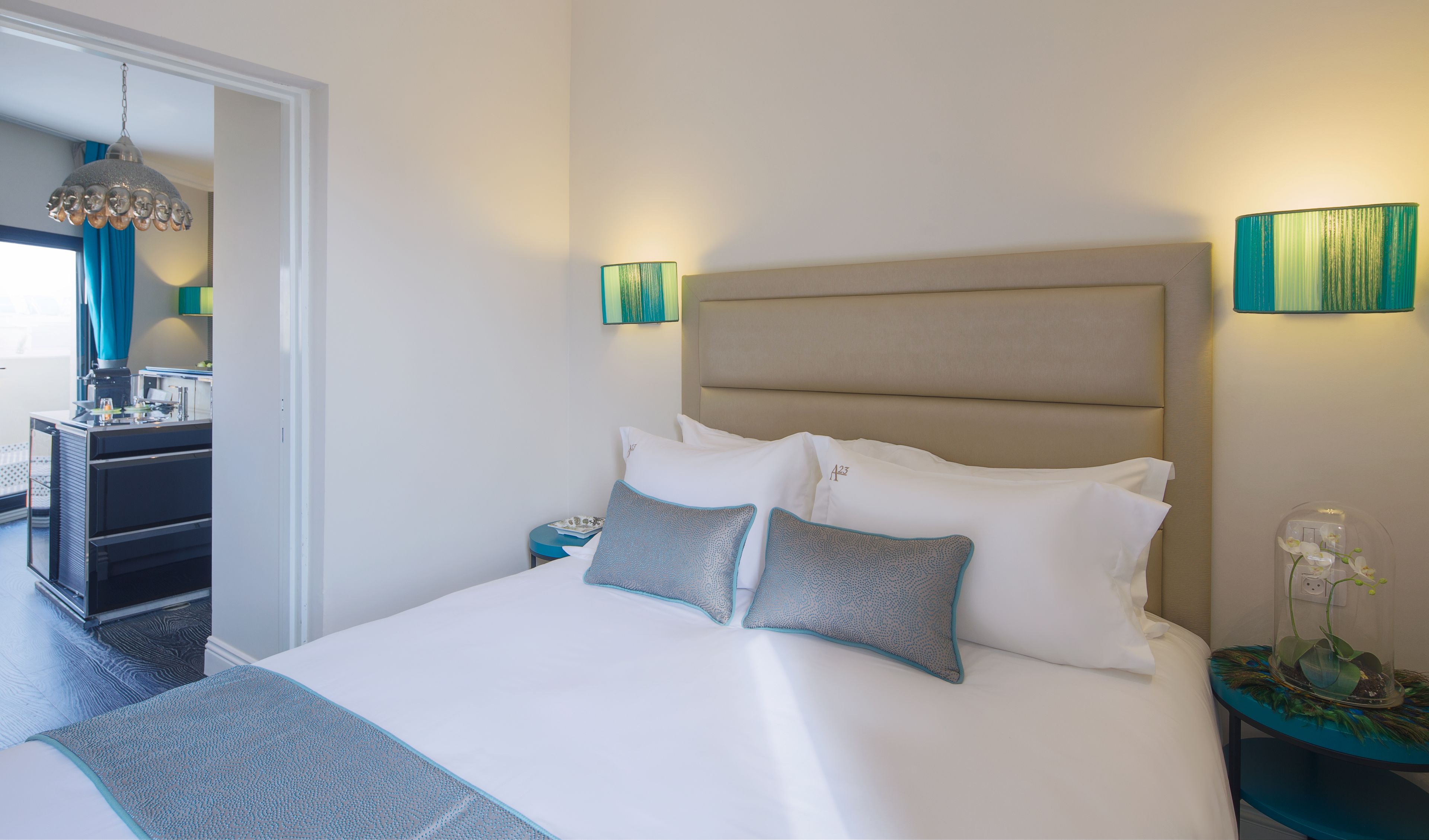 Een net opgemaakt bed met hoofdbord, twee nachtkastjes en een nachttafel met lamp.