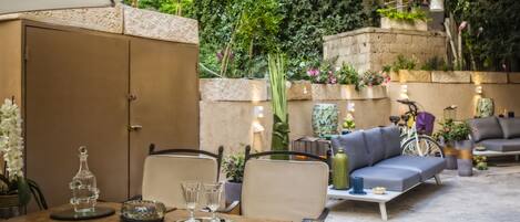 An outdoor patio with a wooden table, chairs, a sofa, and a bicycle.