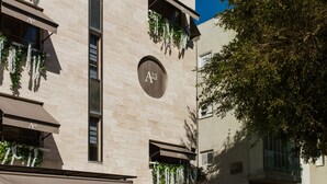 A building with a beige facade, multiple balconies with hanging plants, and a circular sign with 'A23' on it. - A23 Boutique Hotel (Tel Aviv)