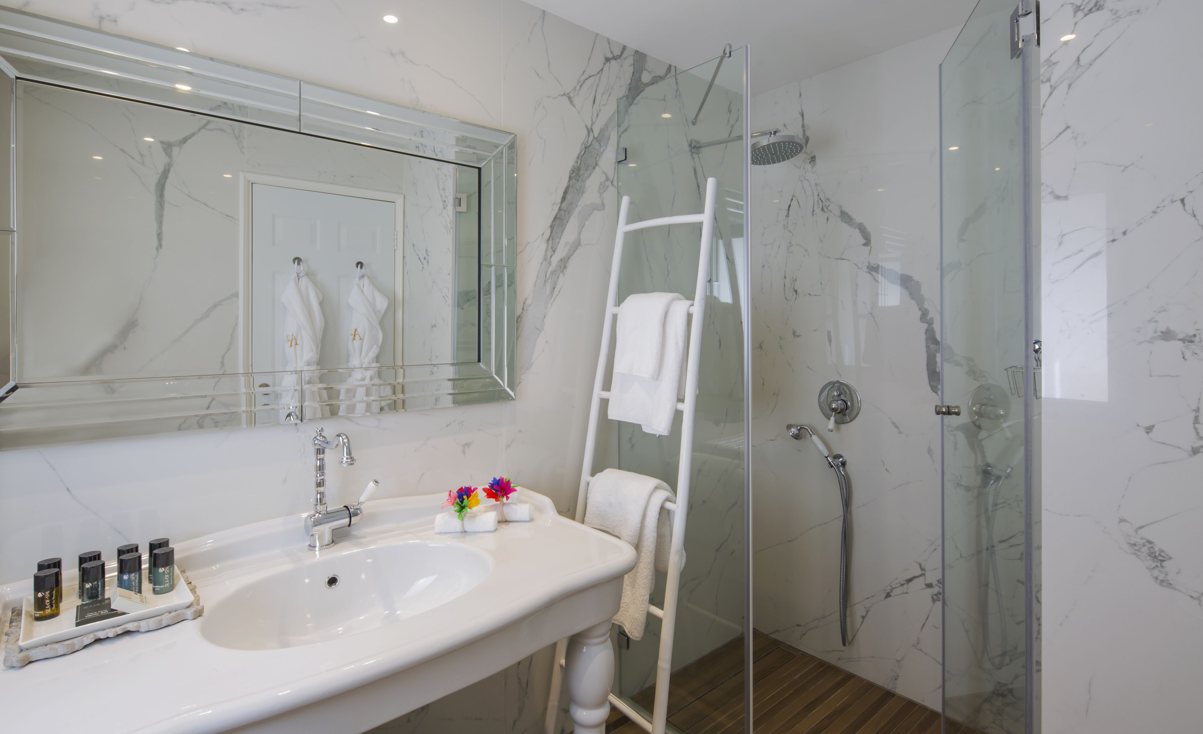 A bathroom with a marble sink, a glass shower enclosure, and a white towel rack.