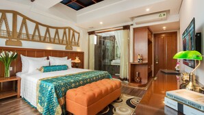 A hotel room with a bed, a bench, a desk, a TV, and a bathroom with a glass shower. - Hanoi Golden Holiday Hotel (Hanoi)