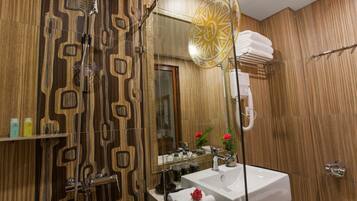Une salle de bain avec un meuble-lavabo en bois, un grand miroir et une douche agrémentée d’un rideau de douche aux motifs géométriques.