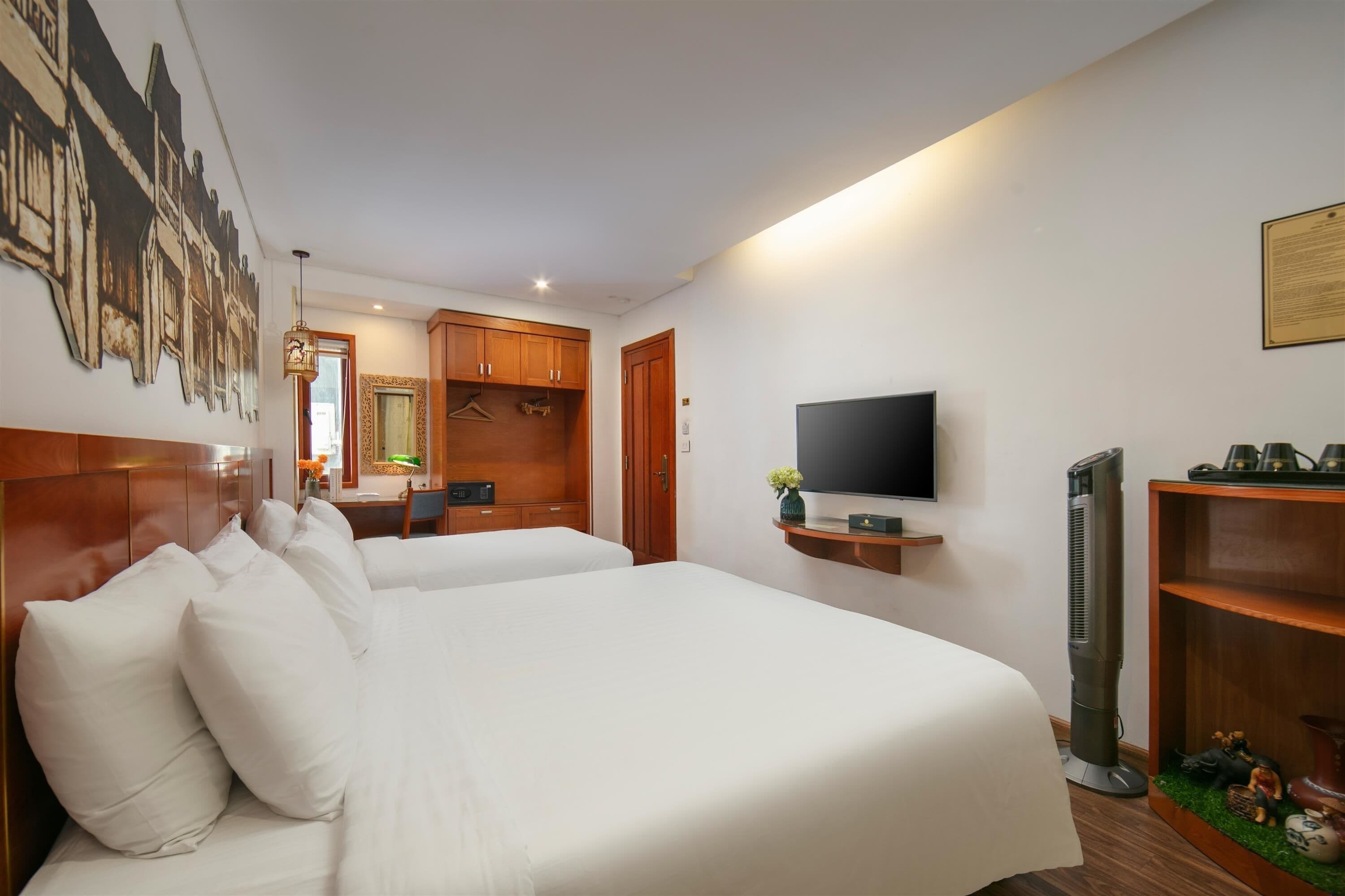 Een hotelkamer met twee bedden, een televisie, een bureau en een spiegel.