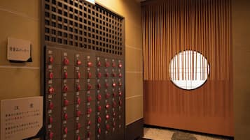 A row of hotel lockers with numbered compartments and red keys.